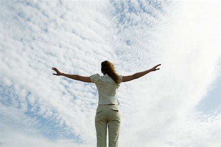 simsearch:632-03652079,k - Woman with arms outstretched, cloudy sky in background, rear view Fotografie stock - Premium Royalty-Free, Codice: 633-03194801
