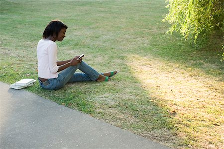 Young woman relaxing in park, text messaging with cell phone Stock Photo - Premium Royalty-Free, Code: 633-03444562