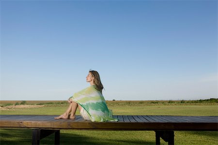 simsearch:633-03444734,k - Woman sitting on deck wrapped in scarf, looking away in thought Stock Photo - Premium Royalty-Free, Code: 633-03444739