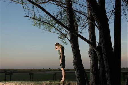 Woman standing on tiZSoes outdoors, holding head and looking down Stock Photo - Premium Royalty-Free, Code: 633-03444745