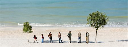 Group of people standing in row chatting between two trees on beach Stock Photo - Premium Royalty-Free, Code: 633-03444978