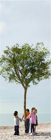 simsearch:632-08130000,k - Group of children holding hands in circle around solitary tree on beach Stock Photo - Premium Royalty-Free, Code: 633-03445002