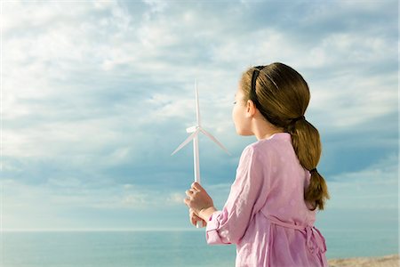 Ecology conceZS, girl blowing on blades of miniature wind turbine Foto de stock - Royalty Free Premium, Número: 633-03445003