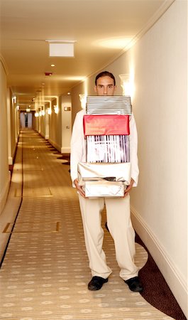 Bellboy carrying gift boxes down hallway Stock Photo - Premium Royalty-Free, Code: 644-01435906