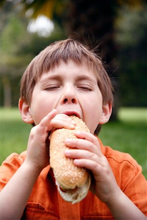 people eating hot dogs - Young boy eating a hot dog Stock Photo - Premium Royalty-Free, Code: 644-01436398