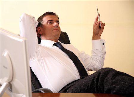 simsearch:645-01538306,k - Businessman sitting at his desk with hands behind his head Stock Photo - Premium Royalty-Free, Code: 644-01436497