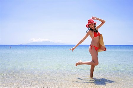 Young woman with bikini, hat, and beach bag Stock Photo - Premium Royalty-Free, Code: 644-01437525