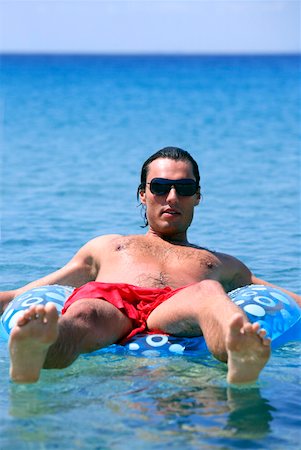 simsearch:644-01437823,k - Young man in water on inflatable life ring Foto de stock - Royalty Free Premium, Número: 644-01437699