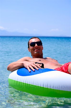 skin and fit - Young man in water on inflatable life ring Stock Photo - Premium Royalty-Free, Code: 644-01437701