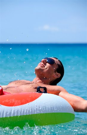 skin and fit - Young man in water on inflatable life ring Stock Photo - Premium Royalty-Free, Code: 644-01437702