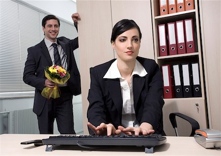 spanish flowers - Male office worker hiding flowers for female colleague Stock Photo - Premium Royalty-Free, Code: 644-01630935