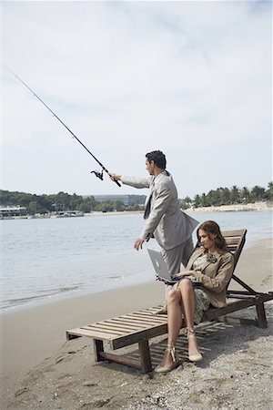 Business couple on beach with fishing rod and laptop Stock Photo - Premium Royalty-Free, Code: 644-01631103