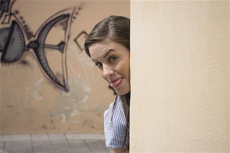 simsearch:644-01631354,k - Woman looking from behind a wall, tongue stuck out Stock Photo - Premium Royalty-Free, Code: 644-01631348