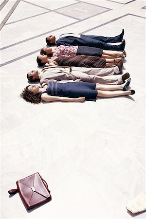Business people lying on the ground in a row Stock Photo - Premium Royalty-Free, Code: 644-01631494