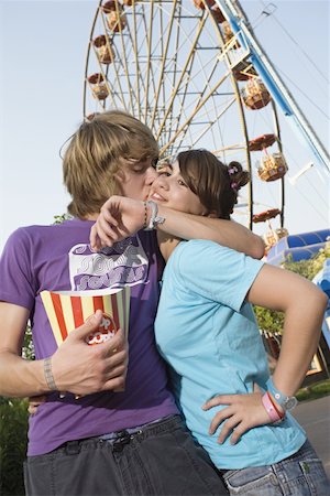 Teenage couple in front of Ferris wheel in amusement park Stock Photo - Premium Royalty-Free, Code: 644-01825537