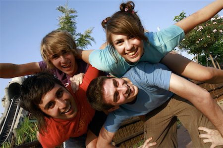 Teenagers playing on piggy back in amusement park Stock Photo - Premium Royalty-Free, Code: 644-01825704