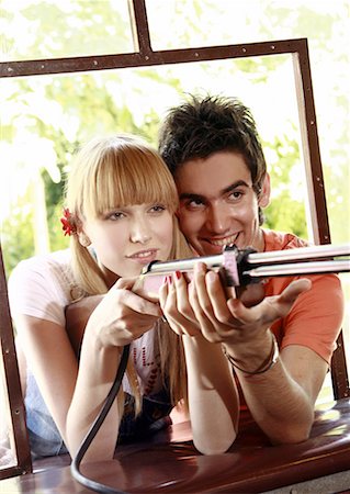 Teenage couple at shooting game in amusement park Stock Photo - Premium Royalty-Free, Code: 644-01825719