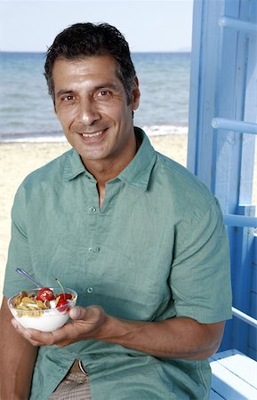 Male mature adult eating breakfast at beach Stock Photo - Premium Royalty-Free, Code: 644-02060567