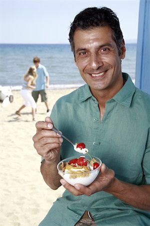 Male mature adult eating breakfast at beach Stock Photo - Premium Royalty-Free, Code: 644-02060569