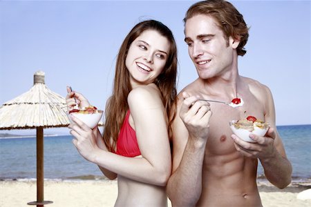 summer eating and clothes - Young adult couple eating breakfast on beach Stock Photo - Premium Royalty-Free, Code: 644-02060582