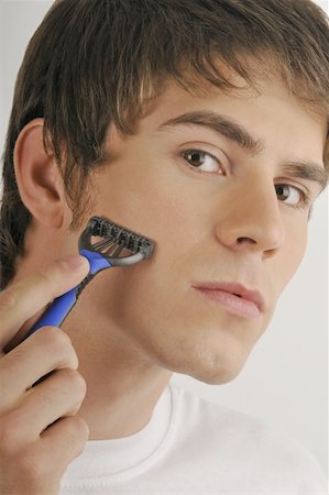 Young male adult shaving face with razor Stock Photo - Premium Royalty-Free, Code: 644-02152759