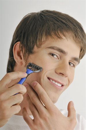 Young male adult shaving face with razor Stock Photo - Premium Royalty-Free, Code: 644-02152766