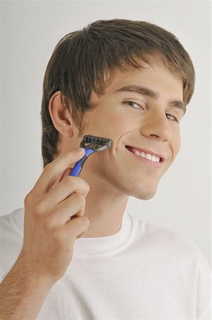 Young male adult shaving face with razor Stock Photo - Premium Royalty-Free, Code: 644-02152763