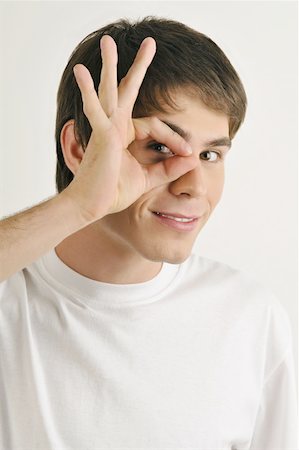 private eye - Young male adult;looking through fingers' hole Stock Photo - Premium Royalty-Free, Code: 644-02152809