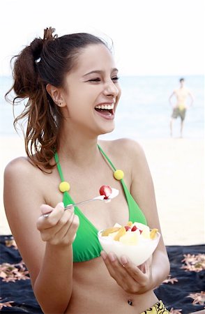 summer eating and clothes - Female young adult eating yogurt and fruit on beach Stock Photo - Premium Royalty-Free, Code: 644-02153261