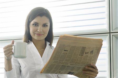 Professional woman with newspaper and coffee cup Stock Photo - Premium Royalty-Free, Code: 644-02923038