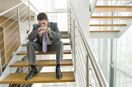 Businessman on office staircase with head on hands Stock Photo - Premium Royalty-Free, Code: 644-02923132