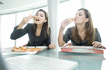 eating takeout - Businesswomen eating pizza at desk Stock Photo - Premium Royalty-Free, Code: 644-02923246