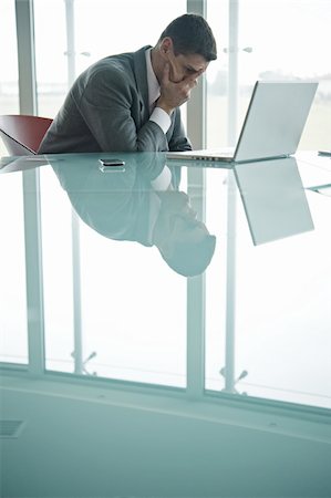 Homme d'affaires à ordinateur portable avec son visage dans sa main Photographie de stock - Premium Libres de Droits, Code: 644-02923250