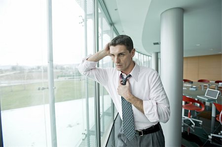 Businessman looking out the window, adjusting tie Stock Photo - Premium Royalty-Free, Code: 644-02923276