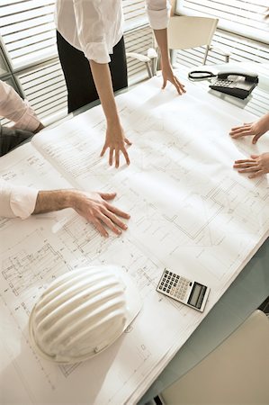 Closeup of professionals looking at architectural plans on desk Stock Photo - Premium Royalty-Free, Code: 644-02923369