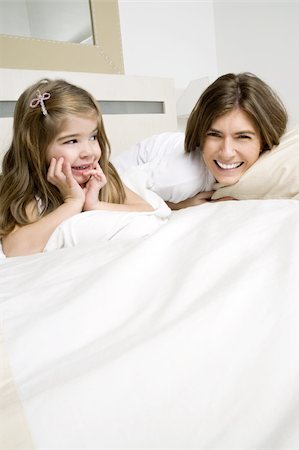 simsearch:644-02923480,k - Jeune femme et une fille sur lit souriant Photographie de stock - Premium Libres de Droits, Code: 644-02923490