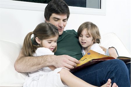 spanish house - Young man on couch with children reading Stock Photo - Premium Royalty-Free, Code: 644-02923551