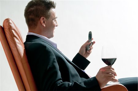 simsearch:644-03405250,k - Jeune homme en costume/tailleur assis avec verre de vin rouge et le téléphone mobile Photographie de stock - Premium Libres de Droits, Code: 644-03405198