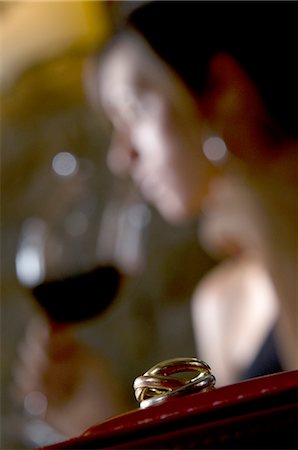 Closeup of ring with young woman in the background drinking red wine Stock Photo - Premium Royalty-Free, Code: 644-03405336