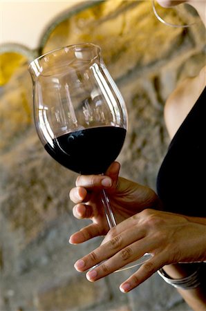 simsearch:644-03405258,k - Gros plan du vin rouge dans un verre tenu par les mains de la jeune femme Photographie de stock - Premium Libres de Droits, Code: 644-03405337