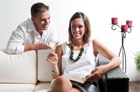 simsearch:644-03405358,k - Young man leaning on couch with young woman with book and white wine Fotografie stock - Premium Royalty-Free, Codice: 644-03405366