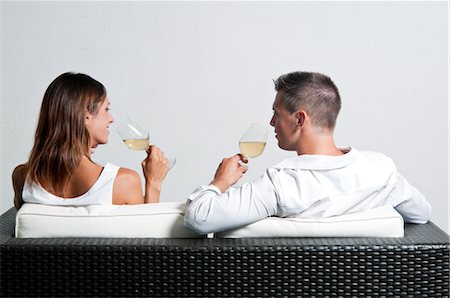 View of couple from the back sitting on couch drinking white wine Stock Photo - Premium Royalty-Free, Code: 644-03405374