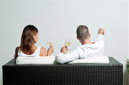 simsearch:644-03405358,k - View of couple from the back sitting on couch drinking white wine, young man pointing Fotografie stock - Premium Royalty-Free, Codice: 644-03405375