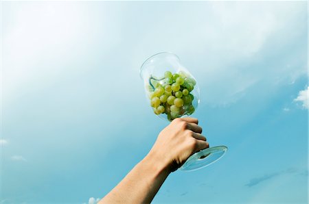 simsearch:644-03405494,k - Hand of young woman holding a wineglass of white grapes in the air Stock Photo - Premium Royalty-Free, Code: 644-03405394