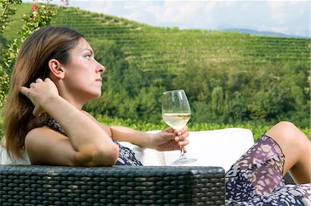 Young woman sitting on couch in vineyard with white wine Stock Photo - Premium Royalty-Free, Code: 644-03405424