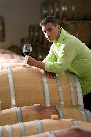 Young man in wine cellar with glass of red wine Stock Photo - Premium Royalty-Free, Code: 644-03405508