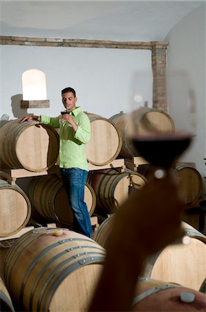 Young man in wine cellar with young woman's hand holding glass of red wine Foto de stock - Sin royalties Premium, Código: 644-03405503