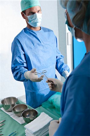 Nurse handing forceps to surgeon in operating room Stock Photo - Premium Royalty-Free, Code: 644-03659434