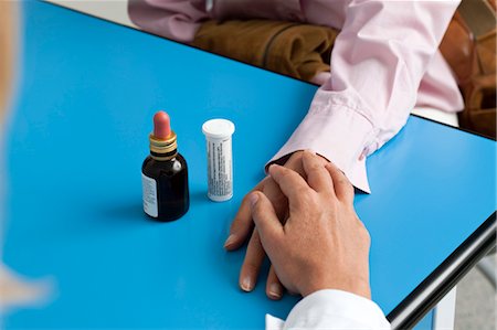 Closeup of doctor's hand holding patient's hand with medicine on table Stock Photo - Premium Royalty-Free, Code: 644-03659538