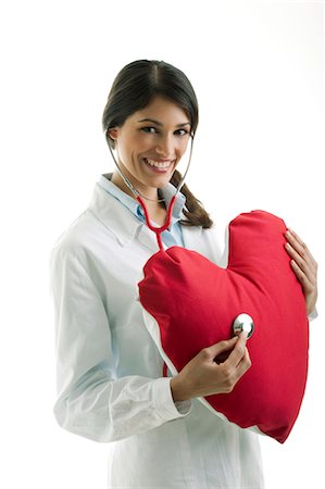 Doctor with stethoscope on heart pillow Stock Photo - Premium Royalty-Free, Code: 644-03659606